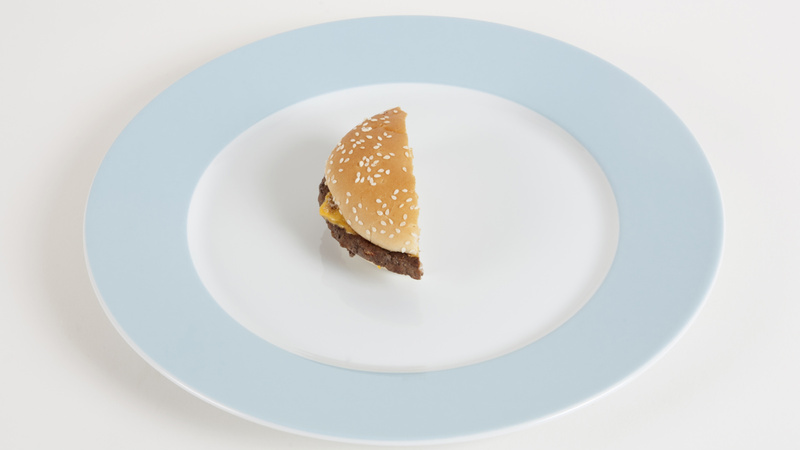 Une assiette blanche avec un bord bleu clair qui contient un tiers de hamburger
