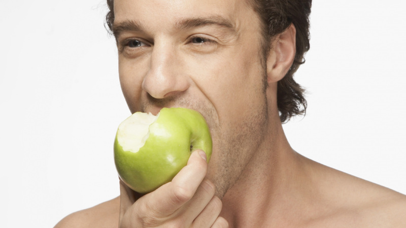 Un homme croque dans une pomme.