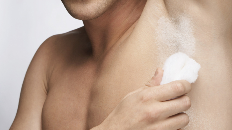Ein Mann, der ein Deodorant unter den Achseln aufträgt.