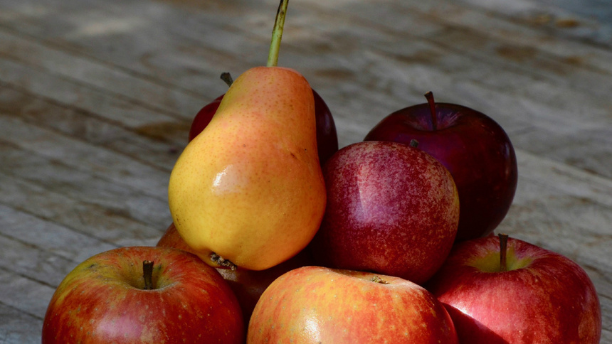 Ein kleiner Haufen von Äpfeln und Birnen ist auf einem Holztisch aufgetürmt
