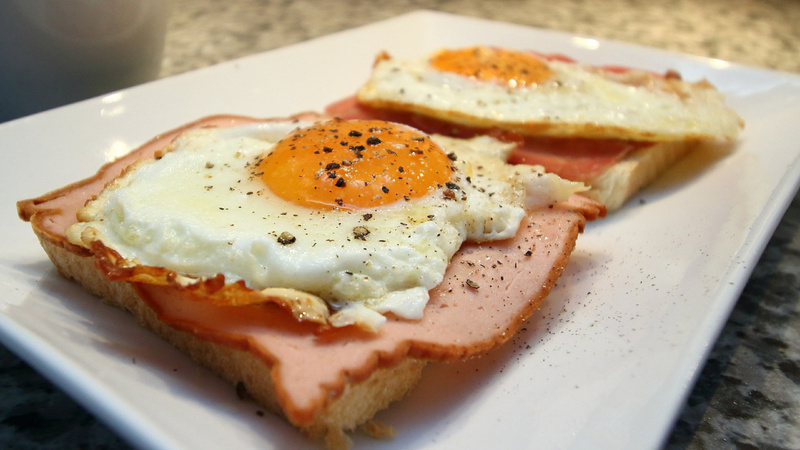 Ernährung, Proteine, Eier: Zwei Scheiben Toast belegt mit Schinken und Spiegelei